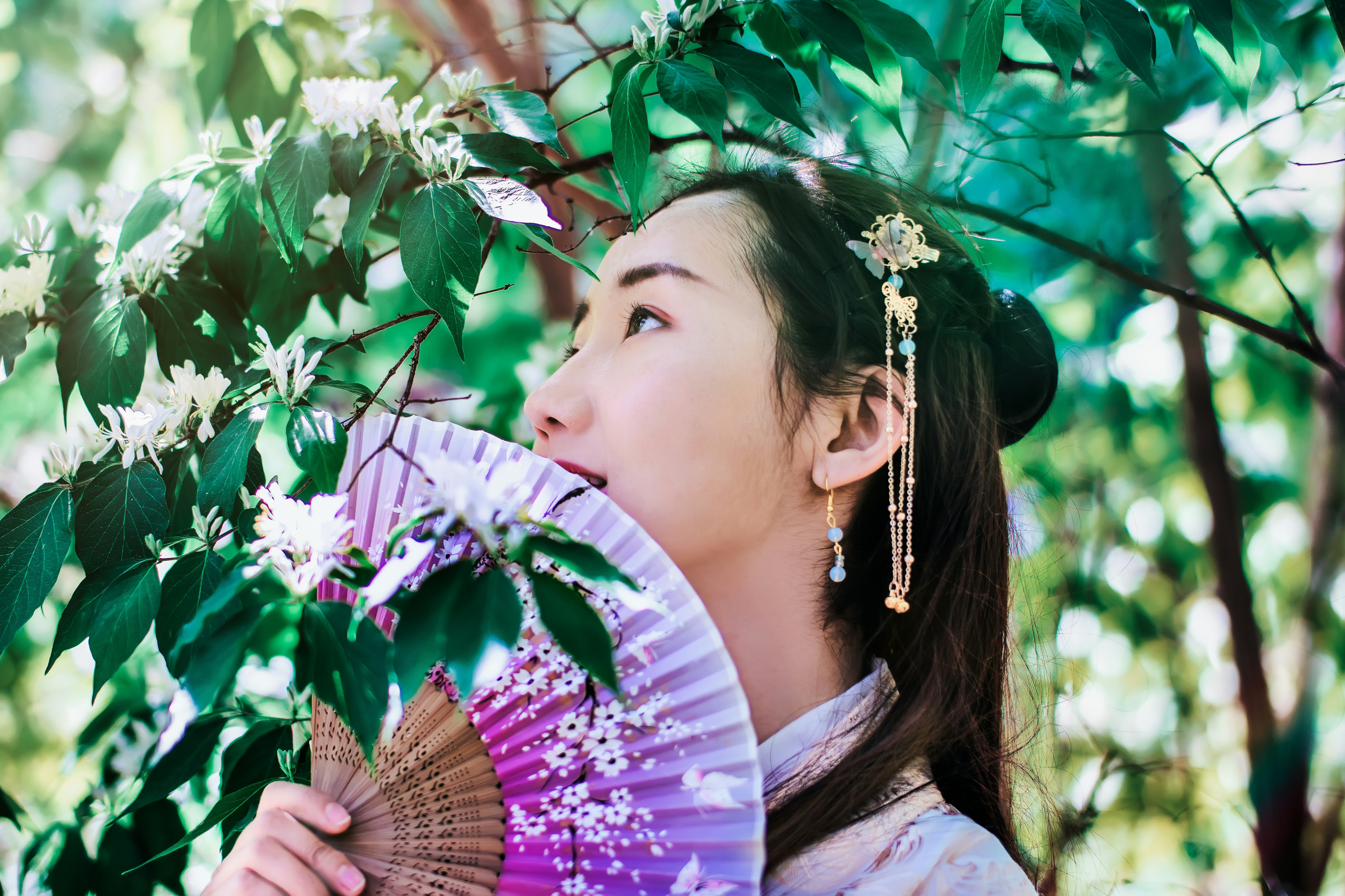 woman holding fan under tree